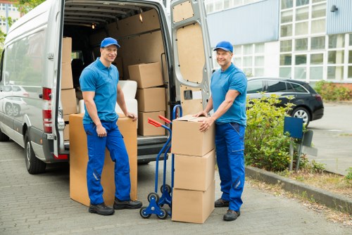 Removal team loading furniture into a truck on a narrow local street